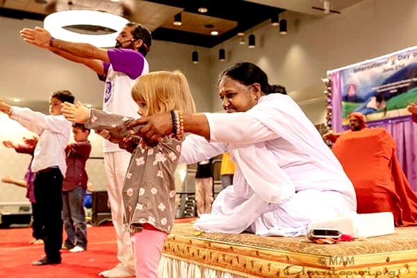 Amma helping child learn yoga